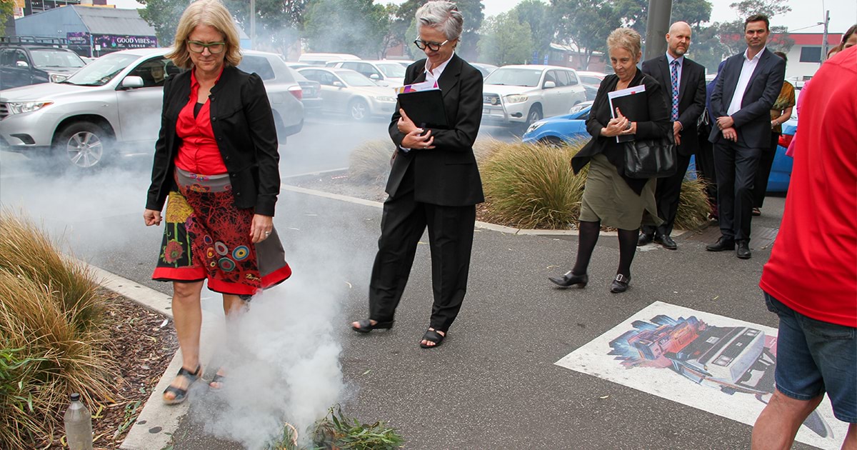 Attendees at the opening of our Sunshine office walk through smoke as part of the Smoking Ceremony, performed by Wurundjeri Elder Uncle Perry Wandin.