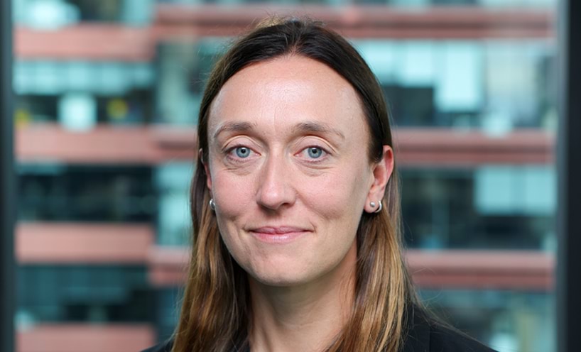 Profile photo of woman with long brown hair smiling at camera.