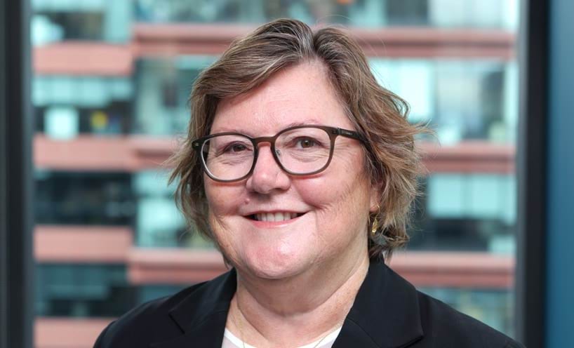 Profile photo of woman with short hair and glasses smiling at camera.